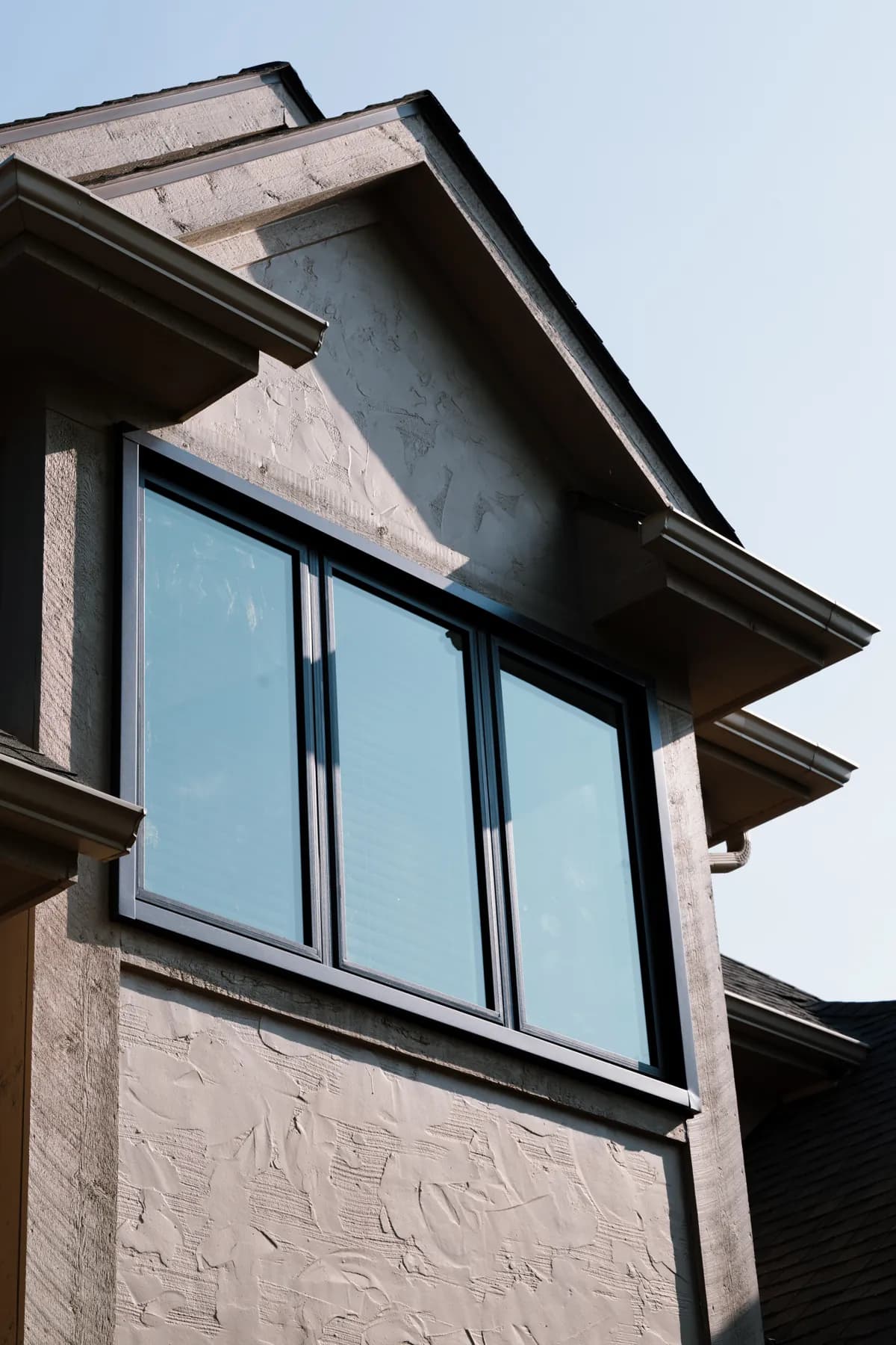 Three-lite black-framed window in a stucco gable, Canton