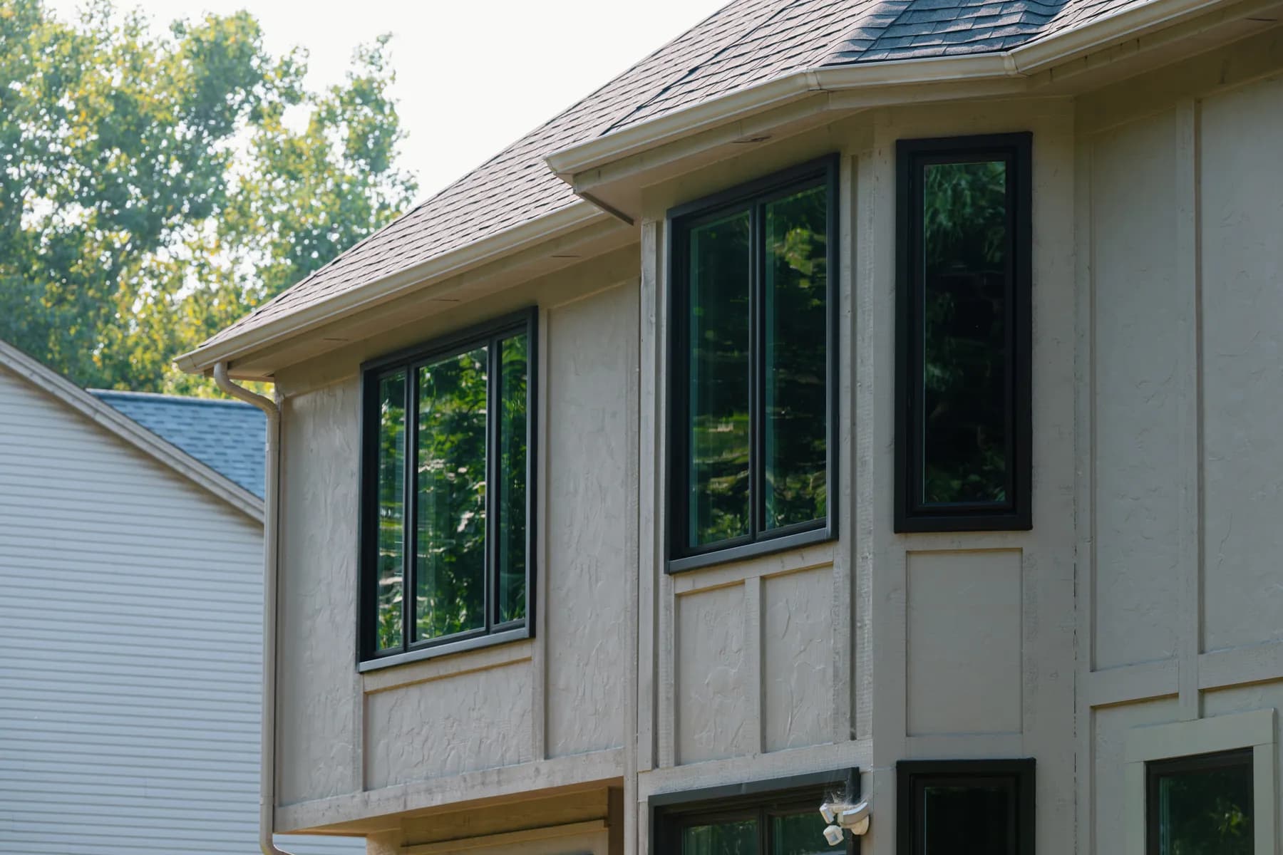 New black-framed windows on a stucco two-storey in Canton