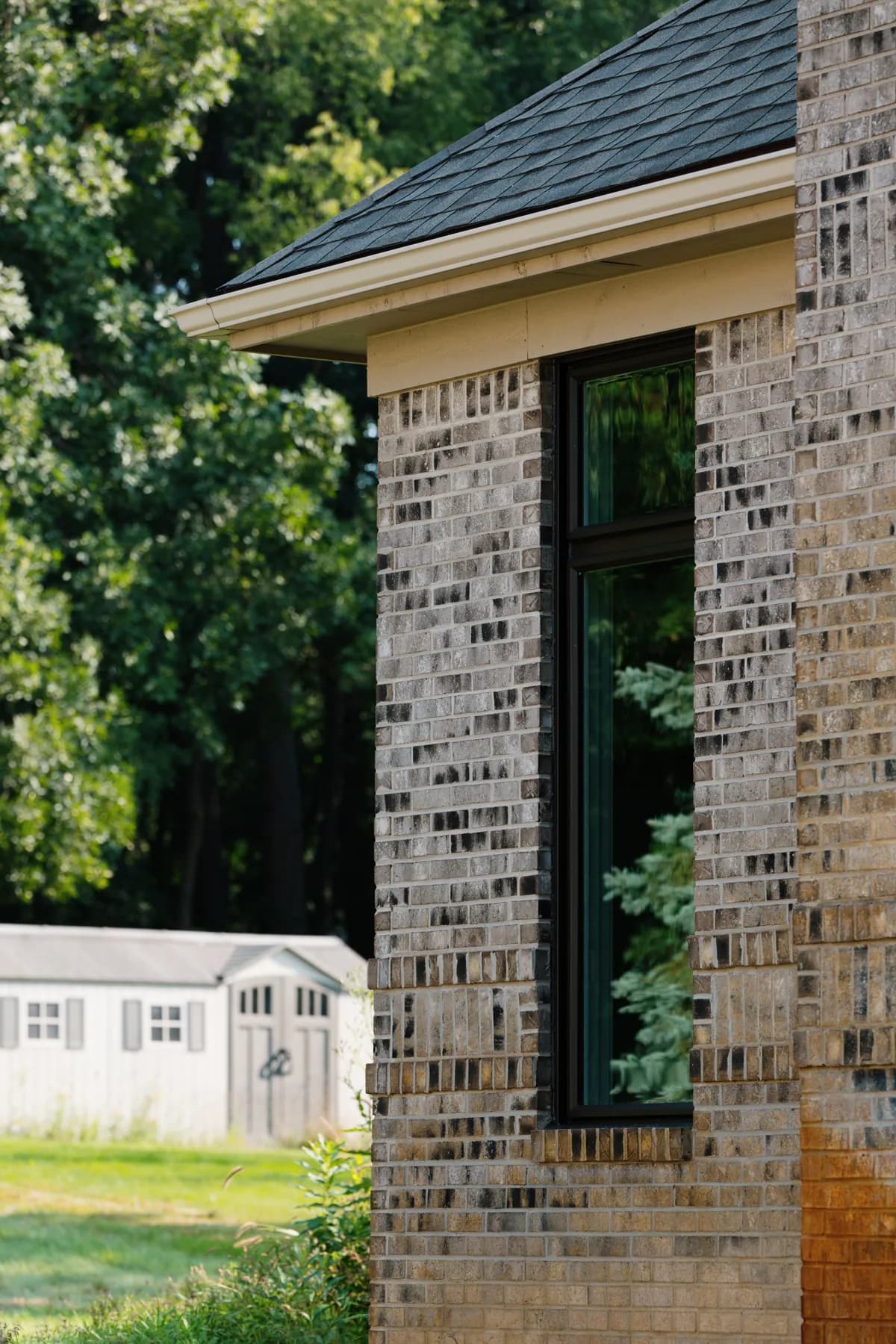 Black-framed replacement window on a brick home in Livonia