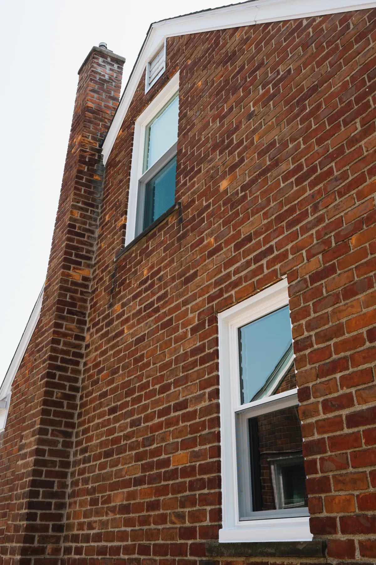 Two new double-hung windows beside the chimney on a Southgate brick cape