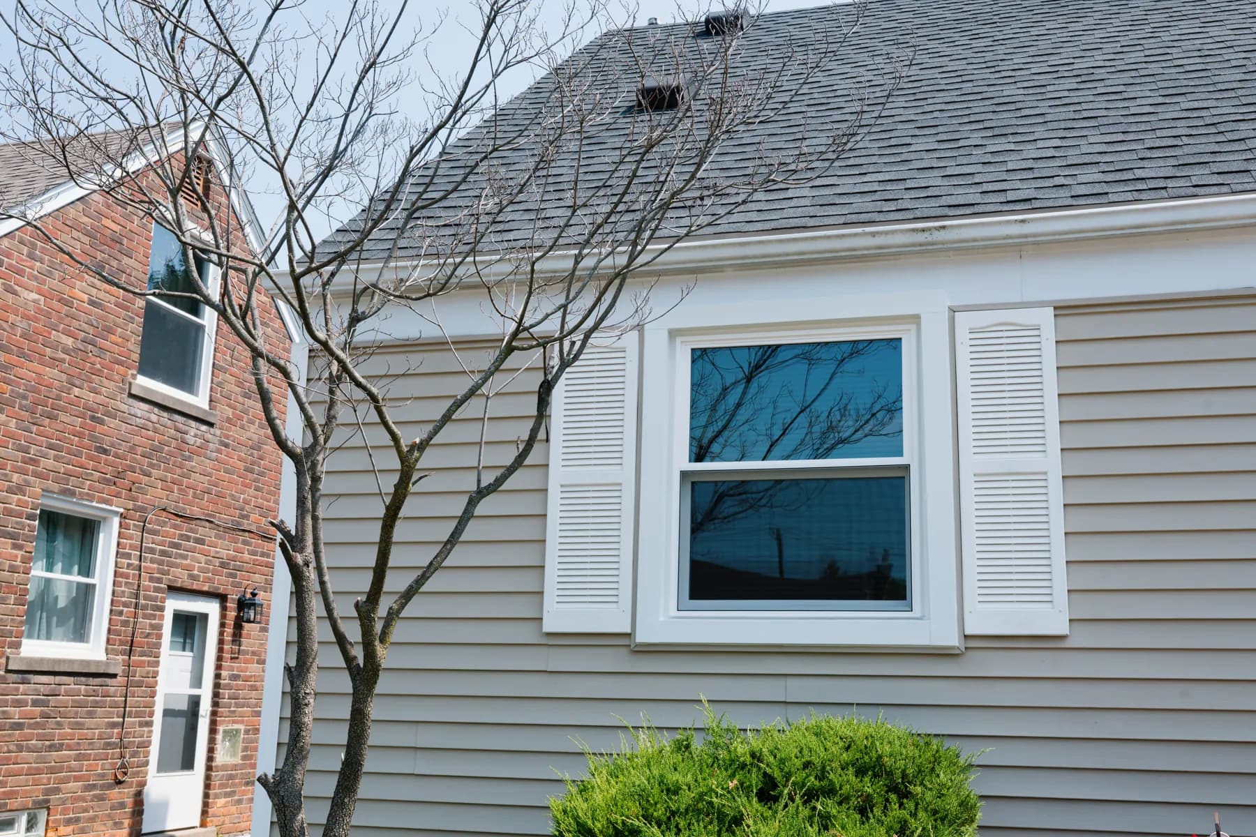 Vinyl siding and a new double-hung window with shutters on a Taylor cape