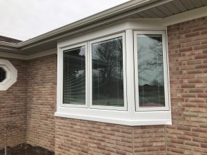 Bay window configuration with white frame set in reddish brick wall of a home